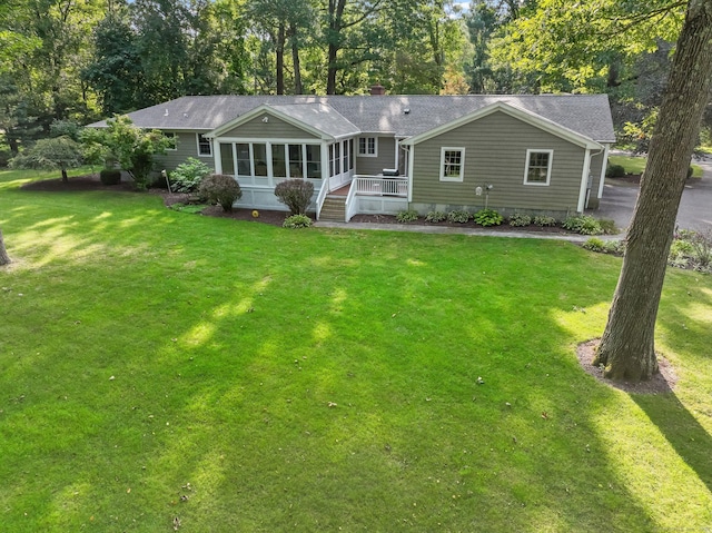 single story home featuring a shingled roof, a front yard, and a sunroom