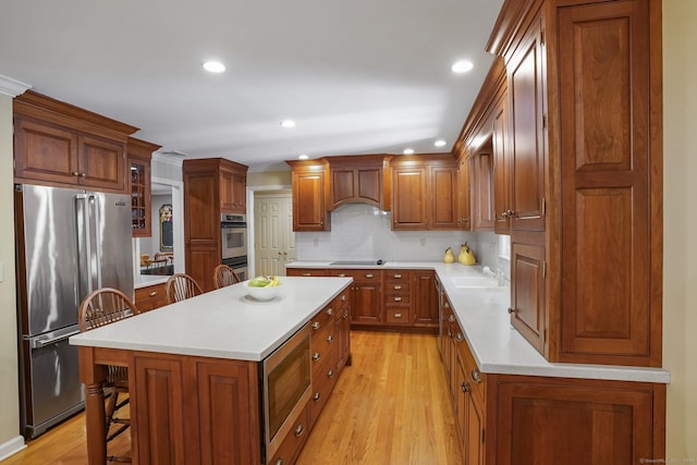 kitchen featuring a breakfast bar, light countertops, premium range hood, and appliances with stainless steel finishes