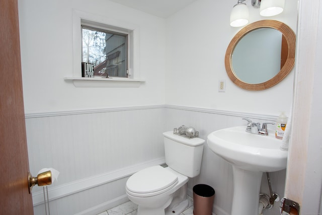 bathroom featuring a sink, toilet, and wainscoting