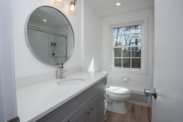 bathroom with vanity, wood finished floors, recessed lighting, a shower, and toilet