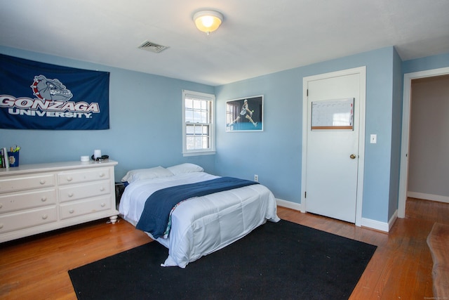 bedroom featuring visible vents, baseboards, and wood finished floors