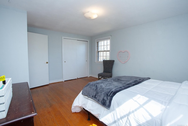 bedroom with a closet, baseboards, and wood finished floors