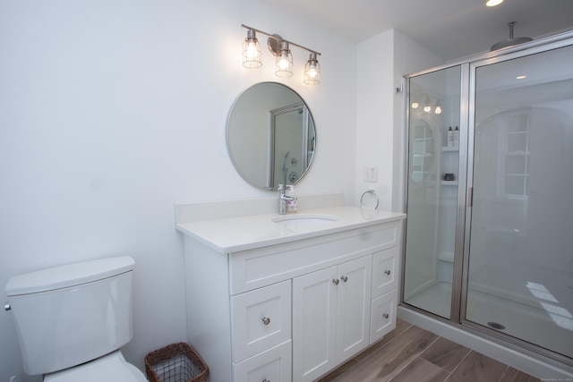 full bath featuring a shower stall, vanity, toilet, and wood finished floors