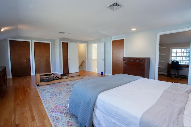 bedroom featuring visible vents, two closets, and wood finished floors