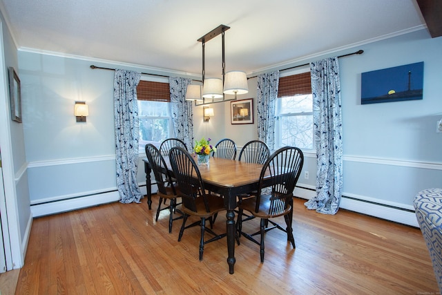 dining space featuring a baseboard heating unit, crown molding, wood finished floors, and a baseboard radiator