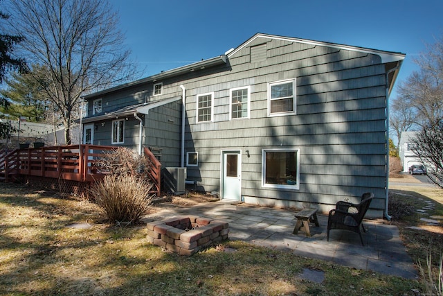 back of property with a wooden deck, a patio area, and a fire pit