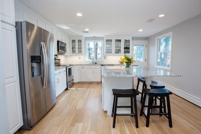 kitchen with backsplash, visible vents, white cabinets, and appliances with stainless steel finishes