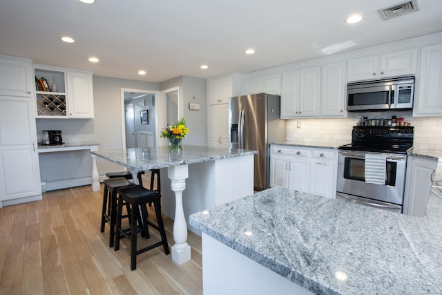 kitchen with open shelves, visible vents, appliances with stainless steel finishes, and white cabinets