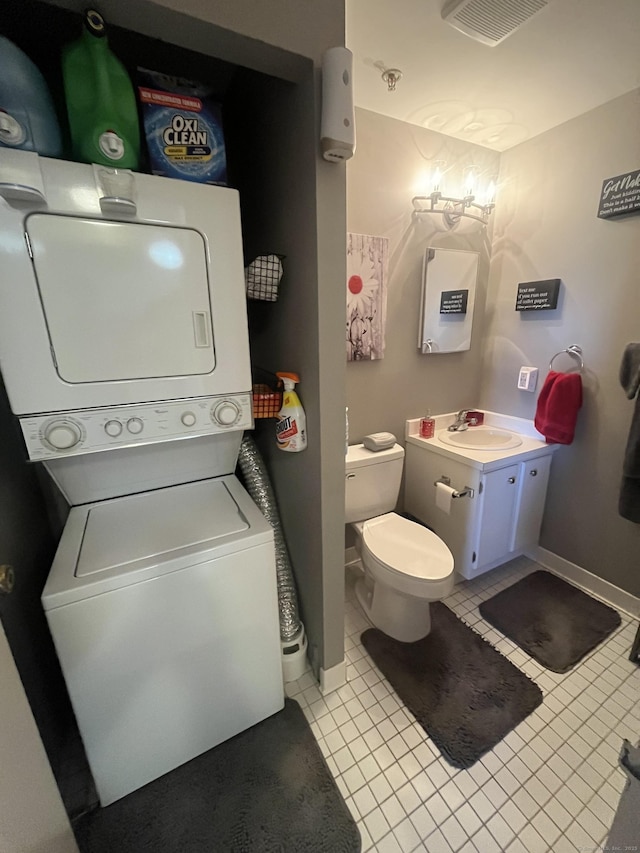 bathroom featuring vanity, visible vents, stacked washing maching and dryer, tile patterned flooring, and toilet