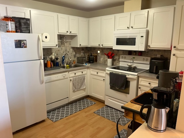 kitchen featuring tasteful backsplash, light wood-style flooring, white cabinets, white appliances, and a sink