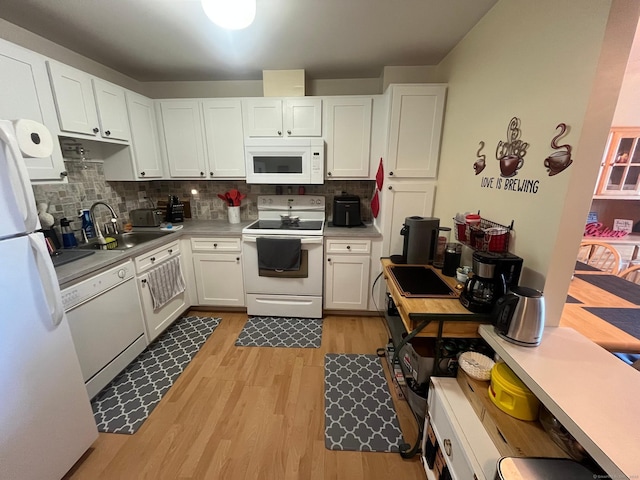 kitchen featuring a sink, backsplash, white appliances, light wood-style floors, and white cabinets