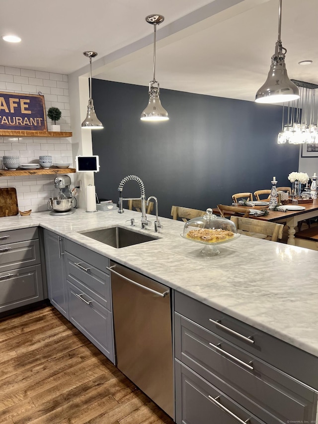 kitchen with a sink, backsplash, dishwasher, gray cabinets, and dark wood-style flooring