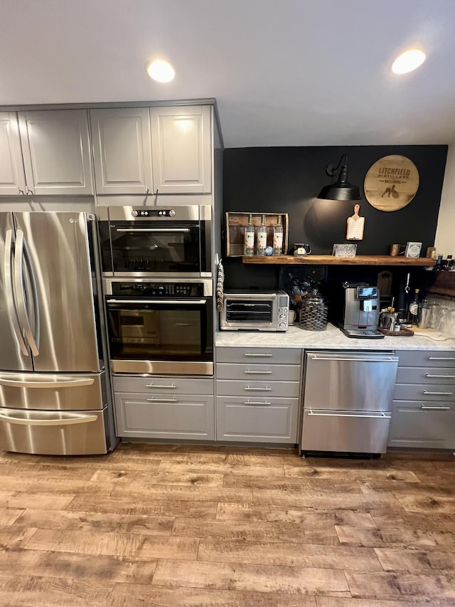 kitchen with a toaster, gray cabinetry, light wood-style floors, and stainless steel appliances