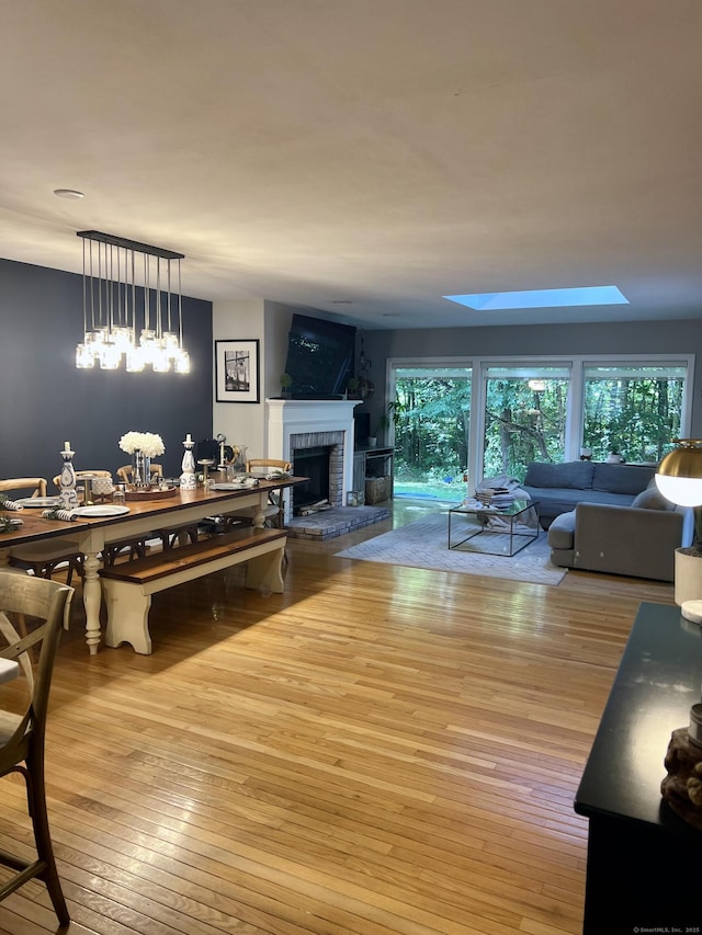 living room featuring a brick fireplace, a skylight, and wood-type flooring