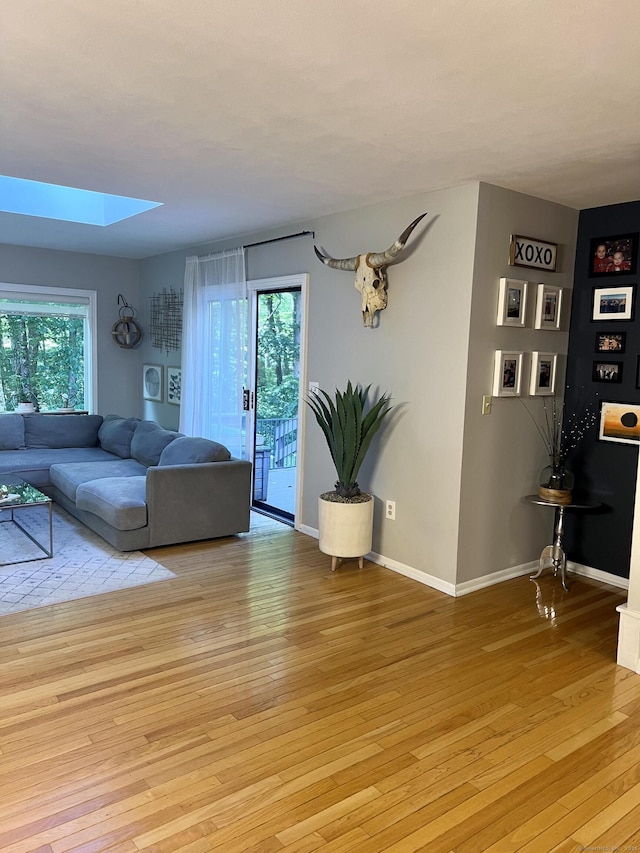 living room featuring a wealth of natural light, light wood-style flooring, and a skylight