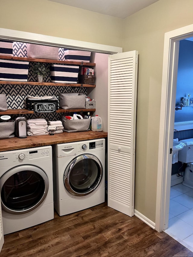 clothes washing area featuring laundry area, washer and dryer, and dark wood-style flooring