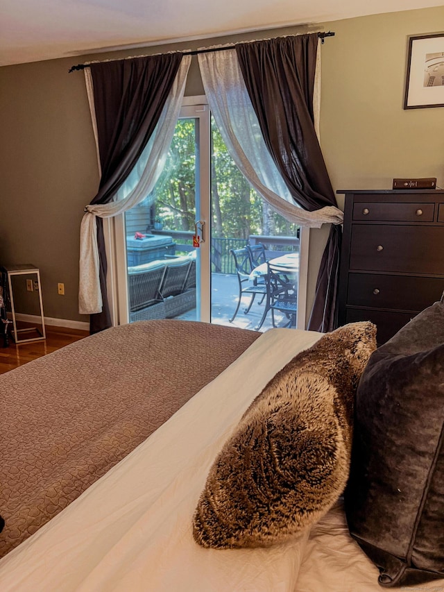 bedroom with wood finished floors, baseboards, and access to outside