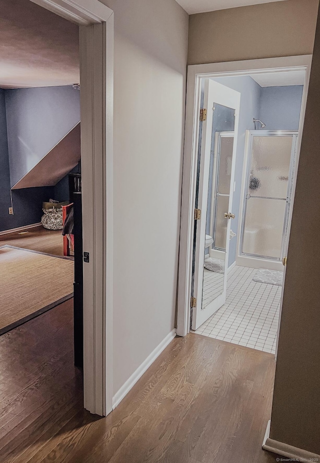 corridor with baseboards and wood finished floors