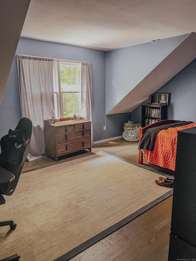 bedroom with baseboards, lofted ceiling, and wood finished floors