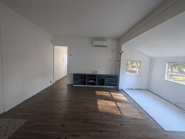 unfurnished living room featuring vaulted ceiling with beams, an AC wall unit, and wood finished floors