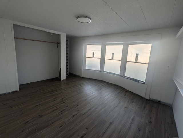 unfurnished bedroom featuring a closet, a textured ceiling, and dark wood-type flooring