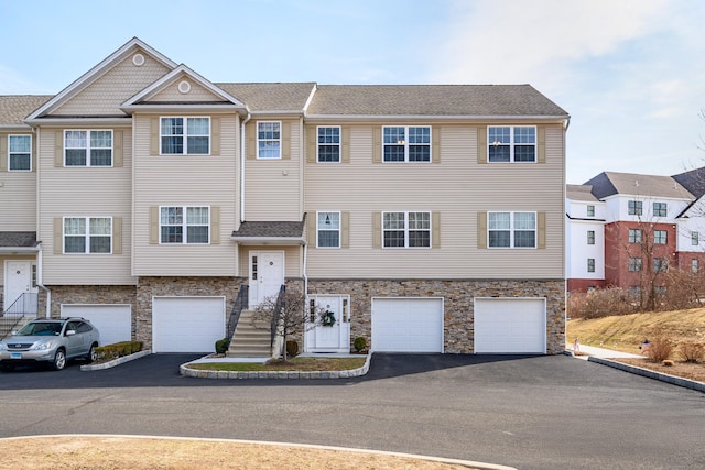 view of property featuring stone siding, driveway, and a garage