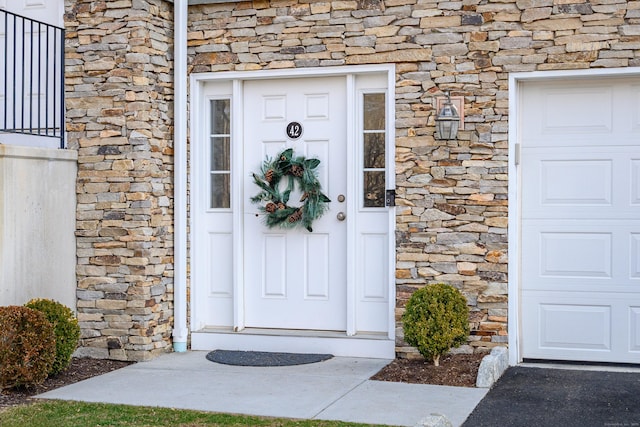 property entrance featuring a garage and stone siding