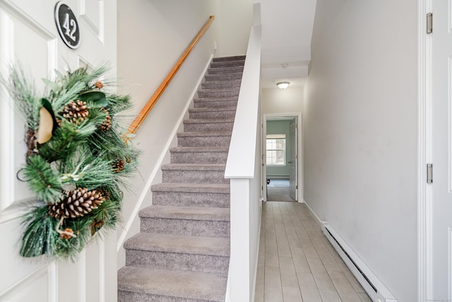 staircase featuring a baseboard radiator, baseboards, and wood finished floors