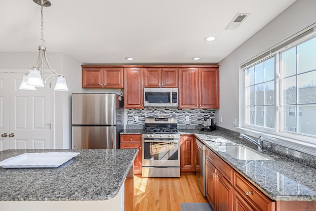 kitchen featuring visible vents, a sink, tasteful backsplash, appliances with stainless steel finishes, and light wood finished floors