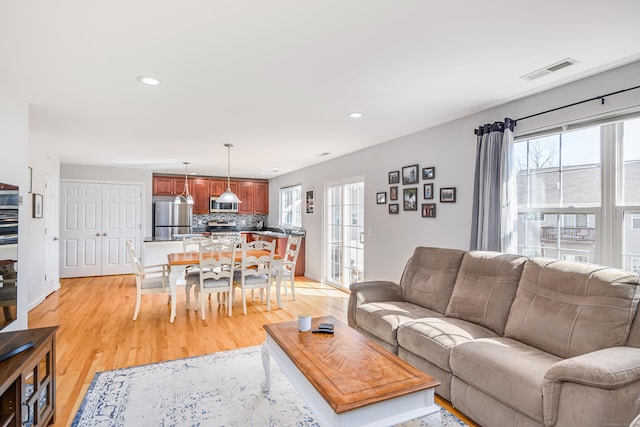 living room with recessed lighting, visible vents, baseboards, and light wood finished floors