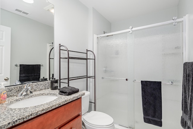 bathroom with visible vents, toilet, a stall shower, and vanity