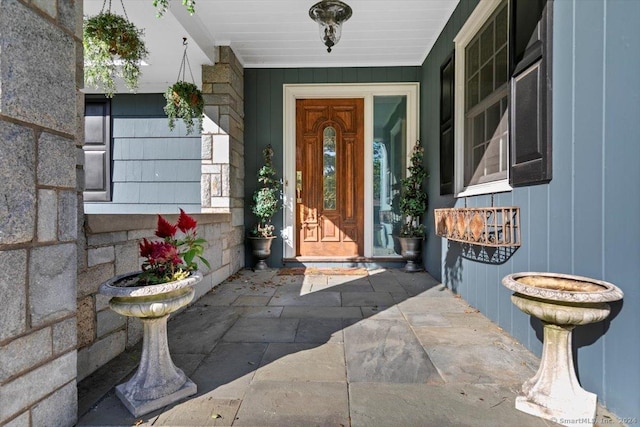 view of exterior entry featuring stone siding and a porch