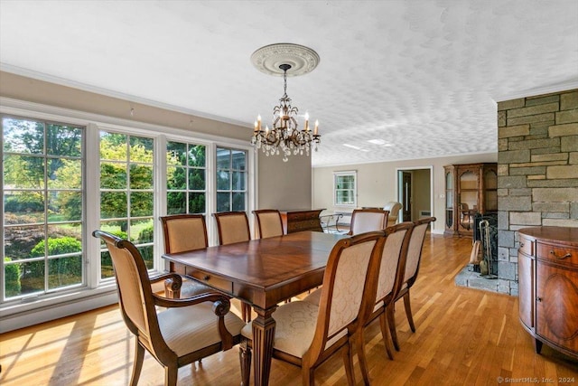 dining room featuring a textured ceiling, a chandelier, and light wood finished floors