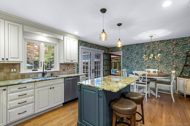 kitchen with wallpapered walls, light wood-type flooring, french doors, stainless steel dishwasher, and a sink