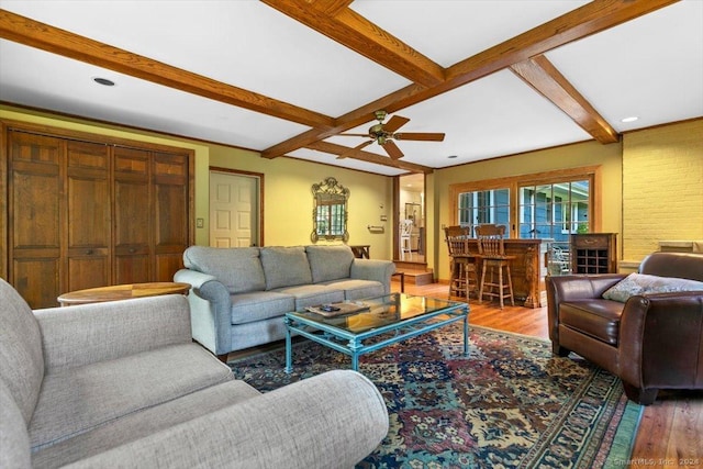 living area with ceiling fan, beam ceiling, wood finished floors, and a dry bar