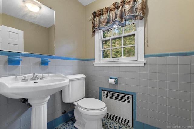 bathroom featuring toilet, tile walls, radiator heating unit, and a wainscoted wall