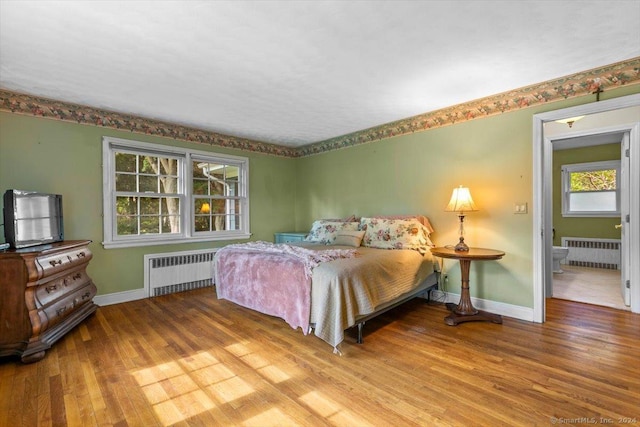 bedroom featuring baseboards, wood finished floors, and radiator heating unit