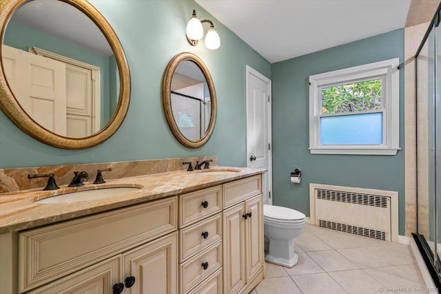 bathroom featuring a sink, toilet, radiator heating unit, and tile patterned flooring