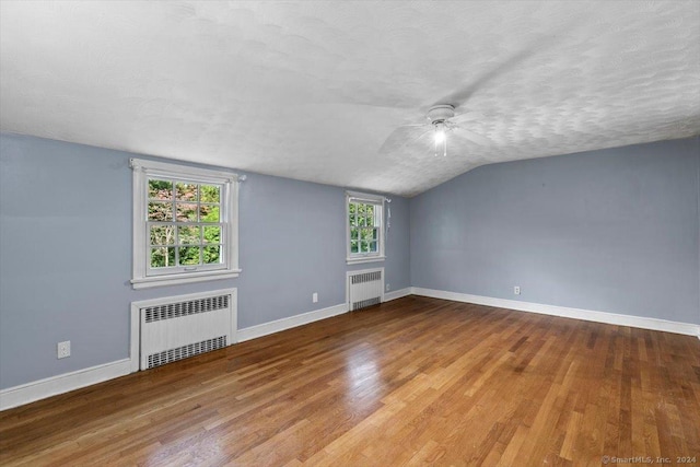 spare room with a textured ceiling, radiator heating unit, baseboards, and wood finished floors