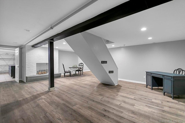 finished basement with recessed lighting, a fireplace, baseboards, and wood finished floors