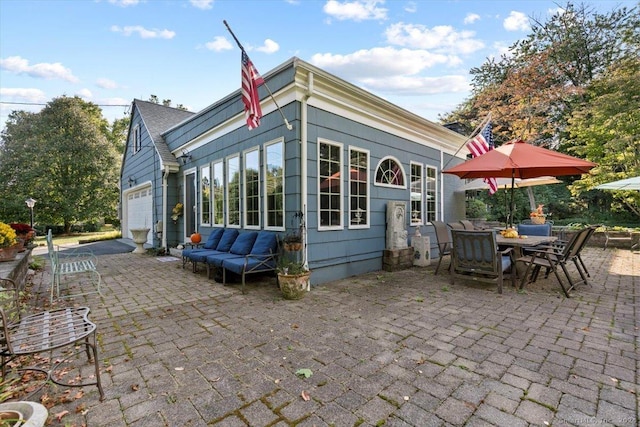 back of property with a patio area, outdoor dining space, an outdoor living space, and a garage