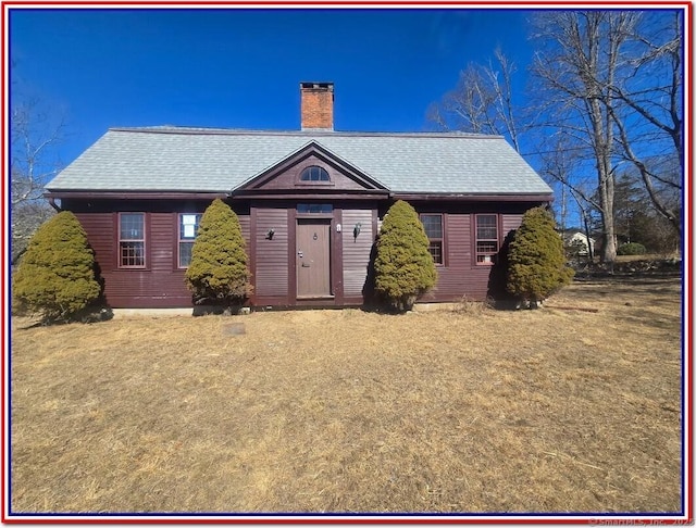 view of front of home with a shingled roof and a chimney