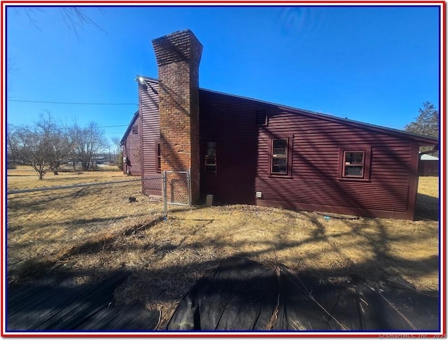 view of side of property featuring a lawn and a chimney