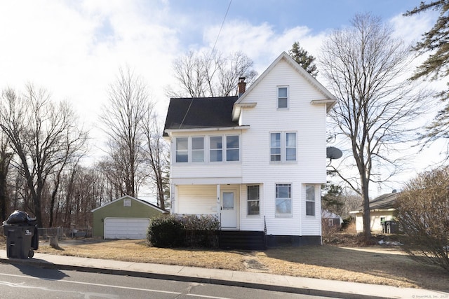 view of front of property featuring an outbuilding, covered porch, a chimney, and a garage