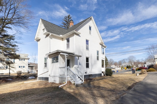 view of front facade featuring roof with shingles and a chimney