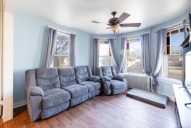 living room featuring baseboards, radiator, wood finished floors, and a ceiling fan