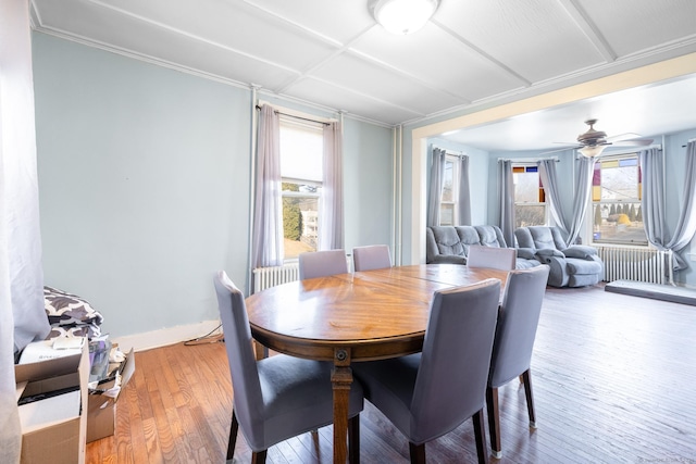 dining room with radiator, a ceiling fan, baseboards, light wood-style flooring, and ornamental molding