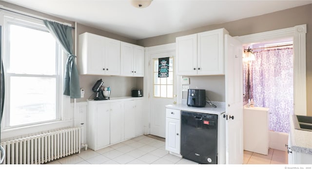 kitchen with black dishwasher, light countertops, radiator heating unit, and white cabinetry