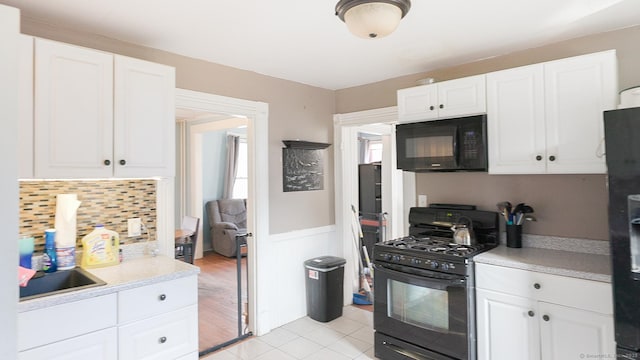 kitchen featuring black appliances, a sink, white cabinets, light countertops, and light tile patterned floors