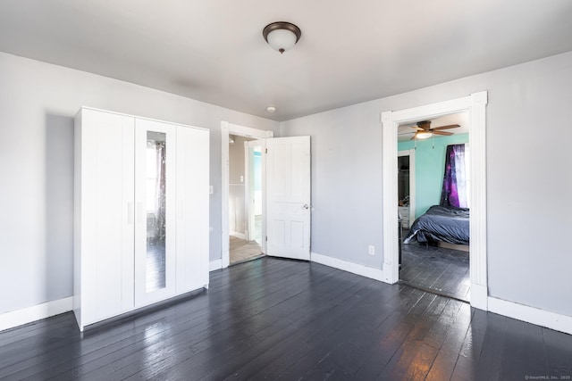 unfurnished bedroom with baseboards, a closet, and dark wood-style flooring